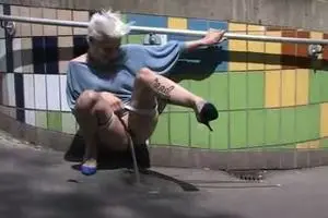 Girl with short hair pissing on the sidewalk