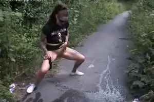 Crazy girl friend pissing on the path between the bushes